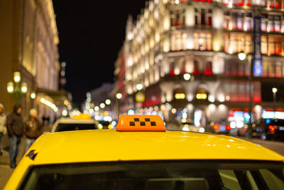 Yellow car on street against illuminated buildings at night