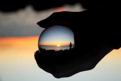 Close-up of silhouette crystal ball against sky during sunset