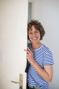 Happy woman wearing eyeglasses standing with house key by door