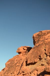 Low angle view of rocky mountain against blue sky