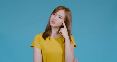 Portrait of beautiful young woman against blue background