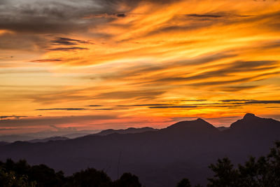 Scenic view of silhouette mountains against orange sky