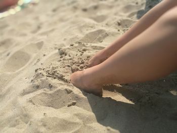 Low section of child on sand at beach