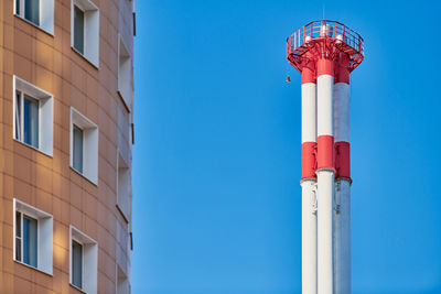 Multistorey building facade and factory chimney. new multi-storey facade, windows and block of flats