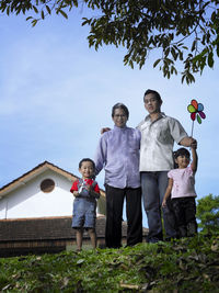 Low angle view of family standing against sky