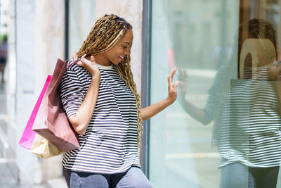 Side view of young woman standing against wall