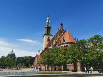 View of buildings and trees against blue sky