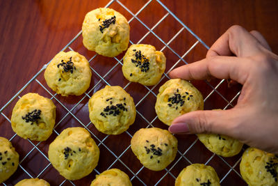 Cropped hand holding cookies over cooling rack