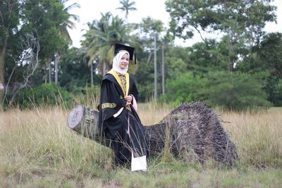 Portrait of smiling young woman sitting on tree stump