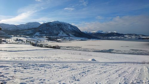 Scenic view of snowcapped mountains in front of landscape against sky on sunny day