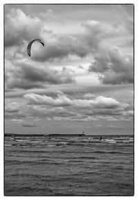 Parachute over sea against cloudy sky