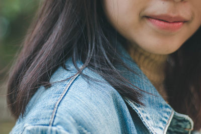 Close-up of smiling young woman wearing denim jacket