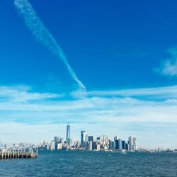 City at waterfront against blue sky