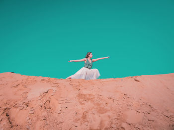 Woman with arms outstretched on sand