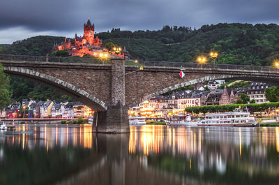 Illuminated bridge over river in city