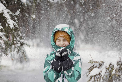 Boy with eyes closed enjoying snowfall at park