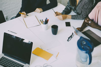 Midsection of creative business people sitting at conference table in board room