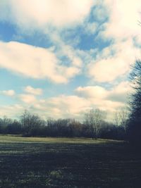 Scenic view of grassy field against cloudy sky