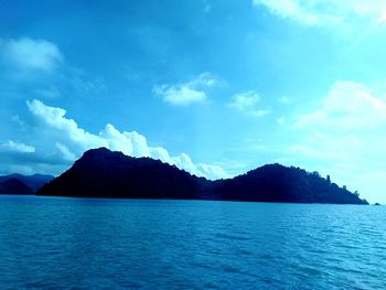 Scenic view of sea by mountains against sky