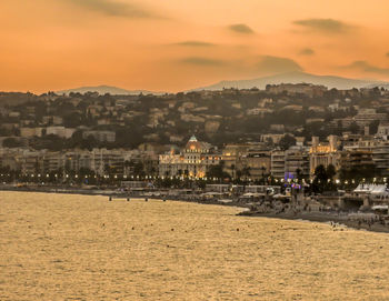 Town by sea against sky during sunset