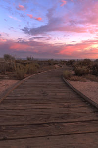 Scenic view of boardwalk against dramatic sky