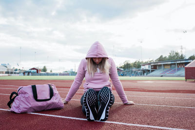 Woman sat on a running track looking nervous