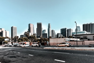 Cars on road in city against clear sky