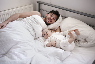 Father with baby son in bed, london, united kingdom