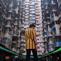 Rear view of man standing against buildings in city