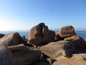 Rocks on beach against clear sky