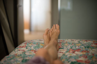 Low section of woman relaxing on bed at home