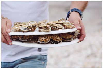 Mid section of a man holding shellfish in plates