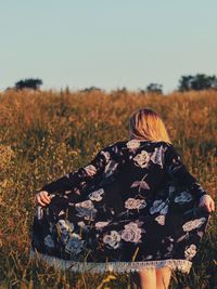 Rear view of woman walking on field against sky