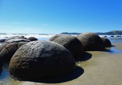 Rocks on beach against clear blue sky
