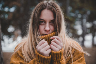 Portrait of young woman wearing sweater standing outdoors during winter