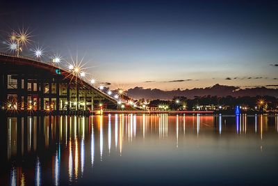 Reflection of illuminated bridge in water at sunset