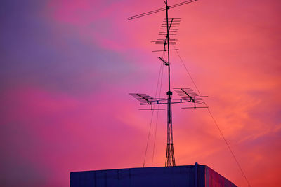 Low angle view of electricity pylon against sky during sunset