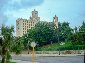 Street amidst buildings and trees against sky