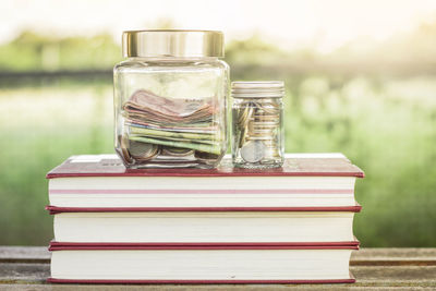 Close-up of currency in jars on stacked books at table