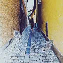 Rear view of woman walking on footpath amidst buildings