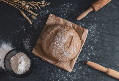 Round bread, sieve, rolling pins and ears on the table.