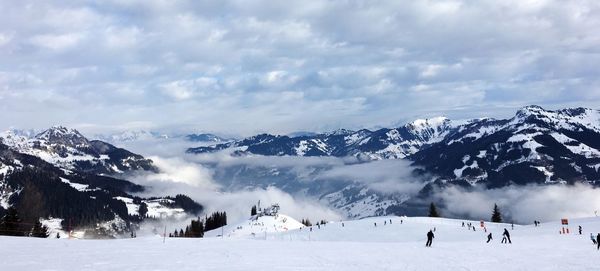 People skiing on snowcapped mountains against sky