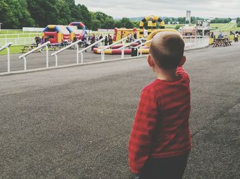 Rear view of boy standing against playground