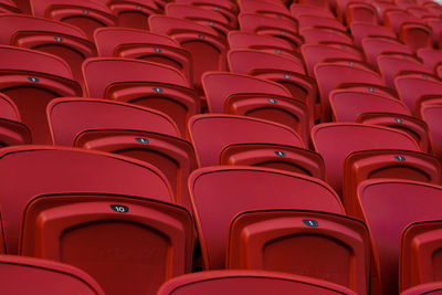 Empty red plastic seats in an empty stadium. many empty seats for spectators in the stands.