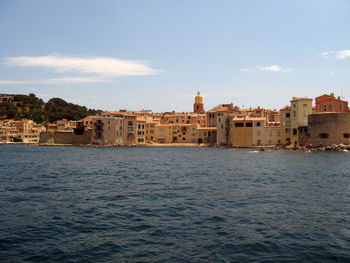 View of buildings by sea against cloudy sky