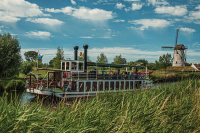 Old steamboat and windmill in canal with bushes near damme. a charming country village in belgium.