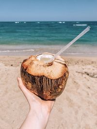 Midsection of person holding ice cream on beach