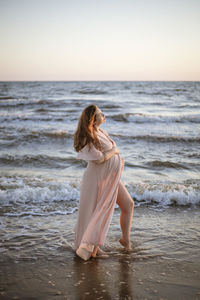 Young pregnant woman with a beautiful sea view on the background. happy and calm pregnant woman