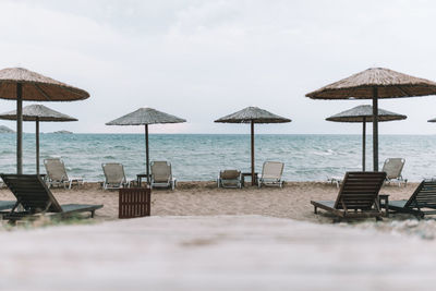 Lounge chairs and parasols on beach against sky
