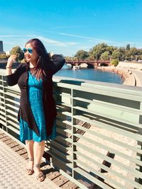 Full length of young woman standing against railing